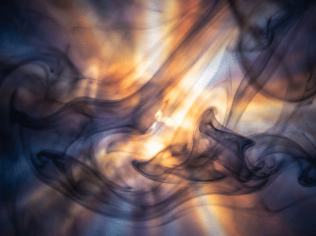 Swirling dark ink or smoke patterns overlapping bright, warm rays of golden and blue light.